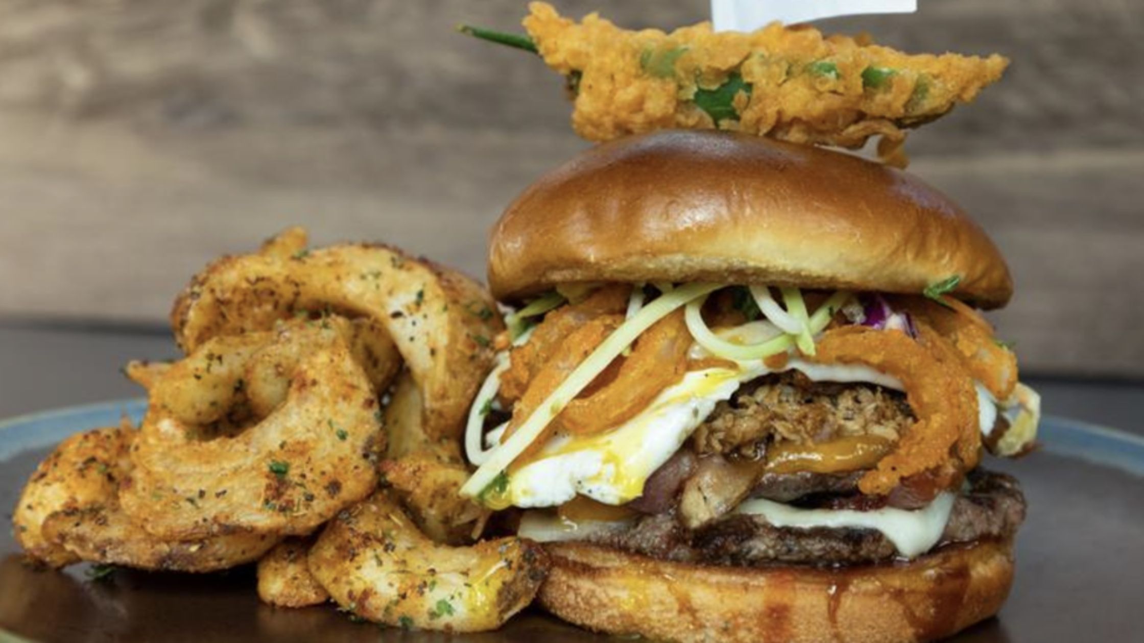 burger topped with fried pepper with a side of fries