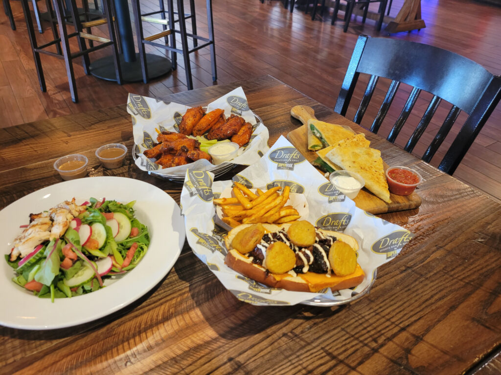 wings, tatchos, and caesar salad on the table of drafts sports bar