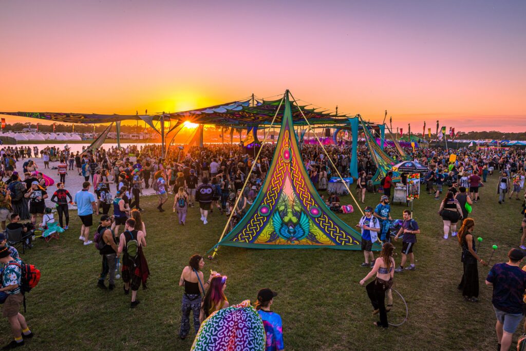 a music festival in florida overlooking a sunset with many people having fun